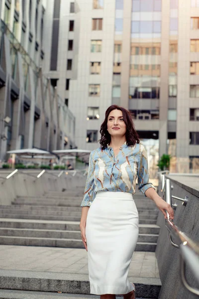 Açık giysiler giyen koyu saçlı güzel orta eged gülümseyen kadın model, yaz günü sokakta poz