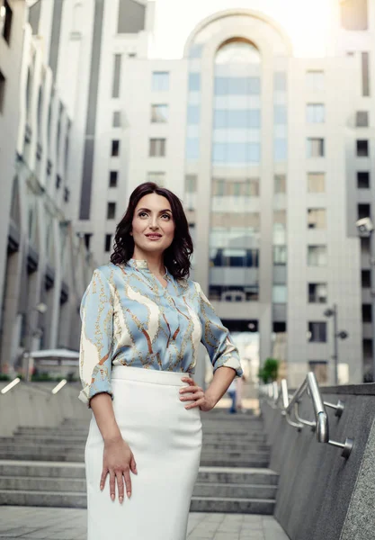 Açık giysiler giyen koyu saçlı güzel orta eged gülümseyen kadın model, yaz günü sokakta poz