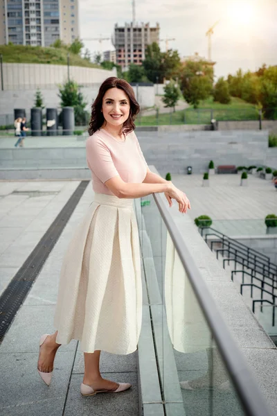 Açık giysiler giyen koyu saçlı güzel orta eged gülümseyen kadın model, yaz günü sokakta poz 