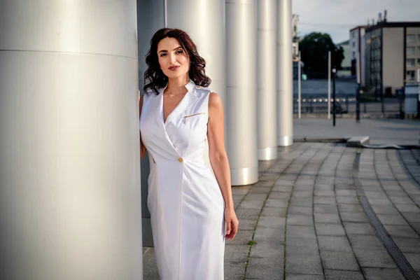 Açık giysiler giyen koyu saçlı güzel orta eged gülümseyen kadın model, yaz günü sokakta poz