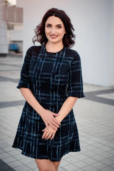 Kısa koyu elbise giyen koyu saçlı güzel orta eged gülümseyen kadın model, yaz günü sokakta poz