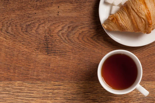 茶杯顶部 茶杯内放曲奇饼和羊角面包 放在深色木制背景桌子上 免版税图库照片