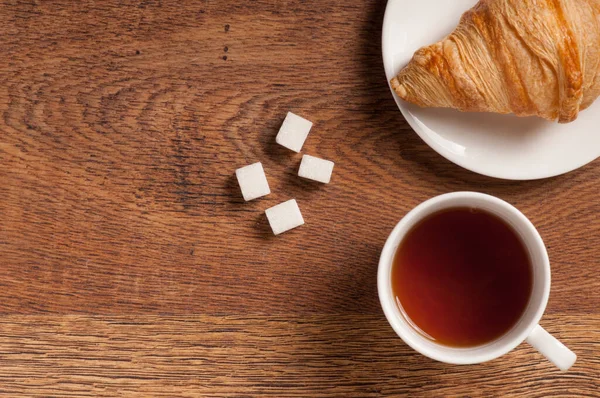 茶杯顶部 茶杯内放曲奇饼和羊角面包 放在深色木制背景桌子上 图库图片