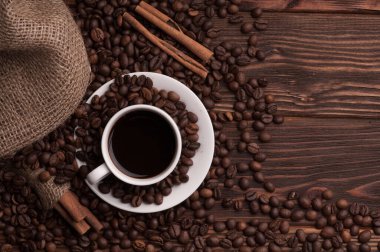 Kahve çekirdekli kahve fincanı tekstil, tarçın ise koyu ahşap arka plan masası.