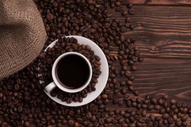 Kahve çekirdekli kahve fincanı tekstil, tarçın ise koyu ahşap arka plan masası.