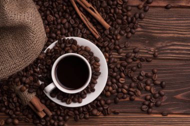 Kahve çekirdekli kahve fincanı tekstil, tarçın ise koyu ahşap arka plan masası.