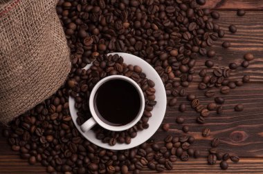 Kahve çekirdekli kahve fincanı tekstil, tarçın ise koyu ahşap arka plan masası.