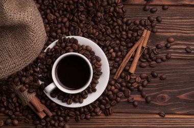 Kahve çekirdekli kahve fincanı tekstil, tarçın ise koyu ahşap arka plan masası.