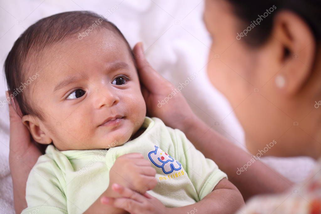 Cheerful young mother playing with newborn baby