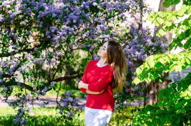 Genç kız bir bahar parkta. Leylak çiçeği arka plan üzerinde. Güzel fotoğraf.