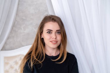 Güzel bir kız bir iç Studio portresi. Büyük yatak arka plan üzerinde.