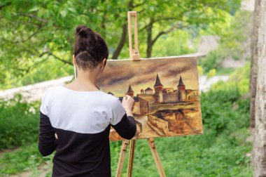 Kadın sanatçı bahçeyi bir resimde boyar. Kamyanets Podolsky Ukrayna.