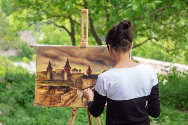 Kadın sanatçı boya bir resim eski bir kale. Kamianets-Podilskyi Ukrayna.