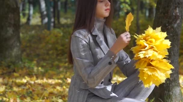 A menina está envolvida em uma grinalda de folha de laranja . — Vídeo de Stock