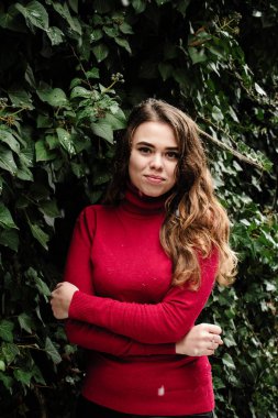 Güzel bir model kırmızı kazaklı kışın Ivy bir halkadır. Bu kar yağıyor, gülümsüyor.