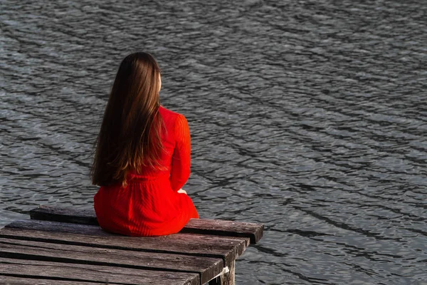 Dziewczyna Czerwonej Sukience Siedzieć Drewniane Murarskie Tle Wody Miejsce — Zdjęcie stockowe