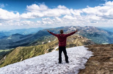 Genç adam ayakta bir dağ ve zevk vadi manzaralı üzerine kaldırdı elleriyle