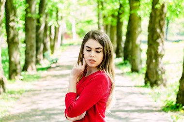 Bir kız portresi. kırmızı bir ceket giymiş. Ağaçlar arka planı.