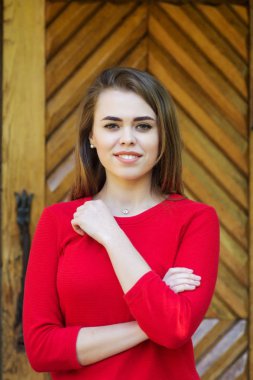 Bir kız portresi. kırmızı bir ceket giymiş. Ahşap kapı arka planı.