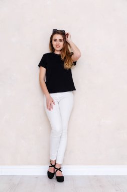 Bir stüdyoda bir kız portresi. Güzel yüzüm. Siyah T-shirt. Beyaz pantolon