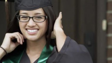 Genç kadın, bir mezuniyet şapkası ve elbisesi, saçlarını ayarlama.