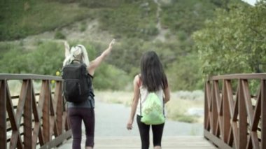 İki kadın bir köprüden diğer tarafa sırt çantaları ile hiking.