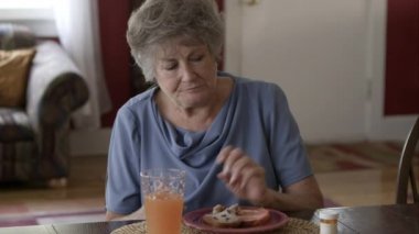 Yaşlı kadın kahvaltı ve alma hapları yemek.