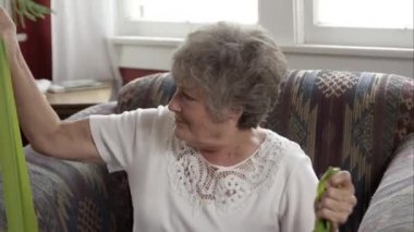 Yaşlı kadın evde lastikleri ile egzersiz yaparak sıkı atış.
