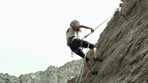 女性は岩の崖をラッペリング — ストック動画