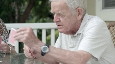 Yaşlı çift verandada kart oynuyor.