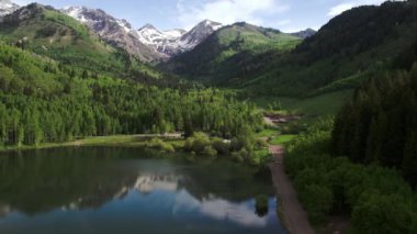 Utah'ta yeşil orman ve dağlarla çevrili gölün havadan görünümü.