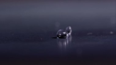Parlak yüzeyde zıplayan su damlacıkları.