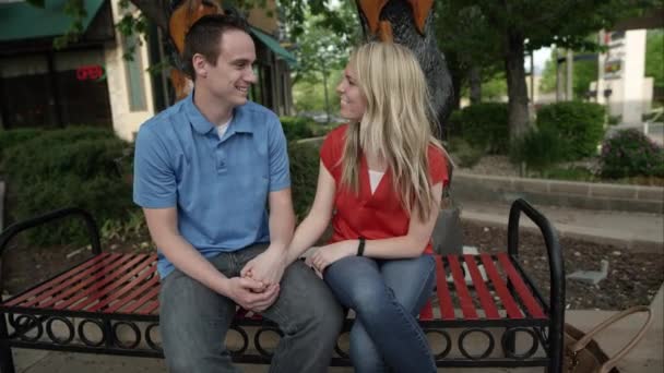 年轻夫妇坐在长凳上笑与能量运动的看法 — 图库视频影像