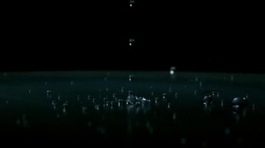 Siyah arka plana düşen su damlacıklarının yavaş hareketi.