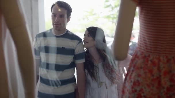 Jeune couple marchant vers le haut et regardant dans la vitrine du magasin à vêtements sur mannequins 