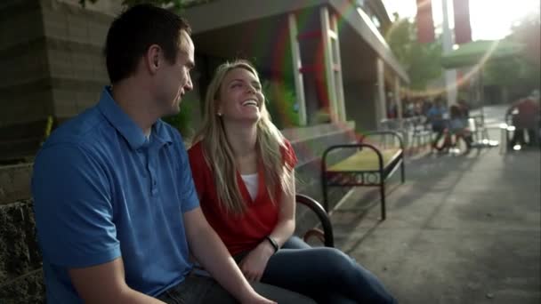 年轻夫妇坐在长椅上笑在购物广场庭院的视图 — 图库视频影像