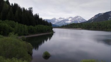 Utah yeşil orman ve dağlar ile çevrili göl üzerinde uçan havadan görünümü.