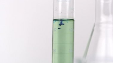 Test tüpünde yeşil sıvıiçine düşen mavi sıvı damla yavaş tava.