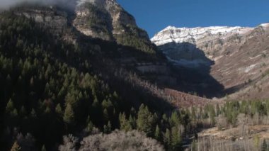 Sundance Utah yakınlarındaki yapraksız ağaçların arkasında dağ yamacından aşağı çekerek havadan görünüm.