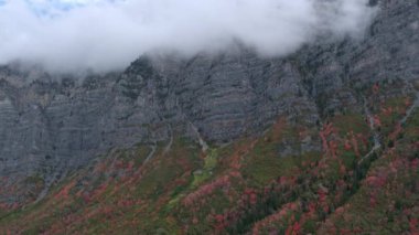Sonbahar yaprakları ve Dağları yakınında asılı bulutlar ile bir dağ tarafından uçan havadan görünümü.