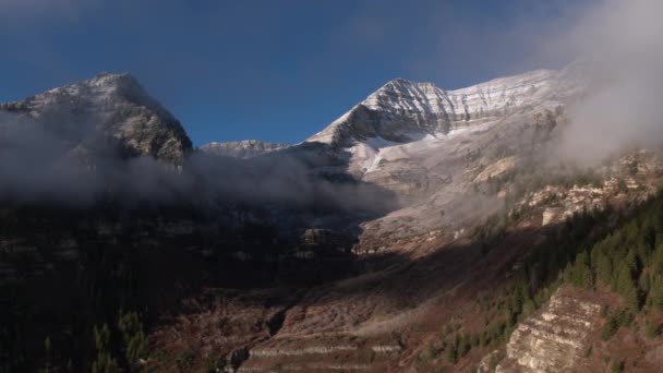 雲がゆっくりと山を隠すように雪に覆われた山のパン空中ビュー — ストック動画