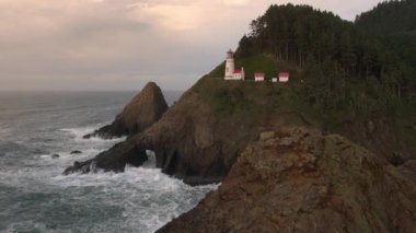 Oregon 'da gün batımı sırasında Heceta Head Lighthouse 'da okyanusun ve kayalıkların havadan görünümü.