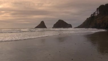 Oregon sahilinde okyanus üzerinde plajdan uçan havadan günbatımı görünümü.