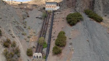 Kayalar ve eski borular arasında bir tepenin üzerinde terk edilmiş binanın havadan görünümü.