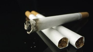 Havada duman hamle olarak siyah masa üstü üzerinde yanan bir sigara ve kül görünümü kaydırma.