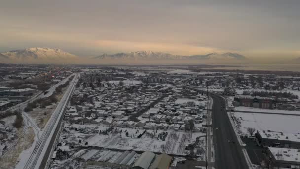 ユタ州のジュネーブ道路上空を飛行する空中図日没の冬の谷を横切って逆転を見る — ストック動画