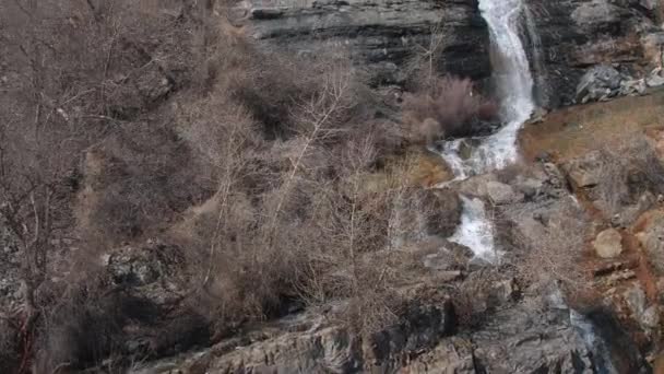 Flyger Förbi Bladlösa Träd Mot Vattenfall Rinner Ner Klippiga Klippan — Stockvideo