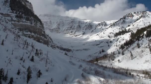 山の谷を覆われて 崖に向かって雪の中を飛ぶ — ストック動画