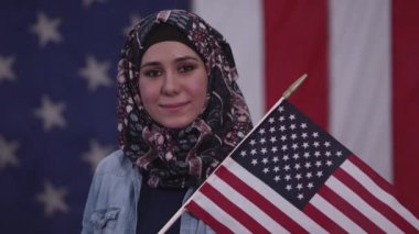 Amerikalı kadın Irak'tan mirasının bir parçası olarak başörtüsü takan Amerikan Bayrağı tutarak gurur gülümsüyor.