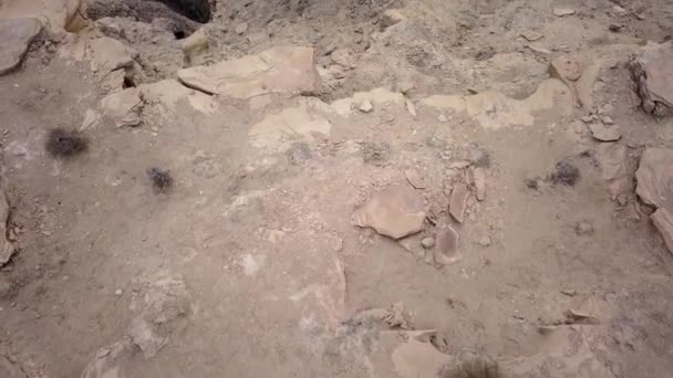 En regardant le sol puis en survolant la falaise en regardant le terrain désertique en dessous .